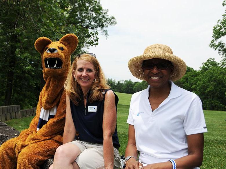 two 工作人员 members posing together with the nittany lion mascot