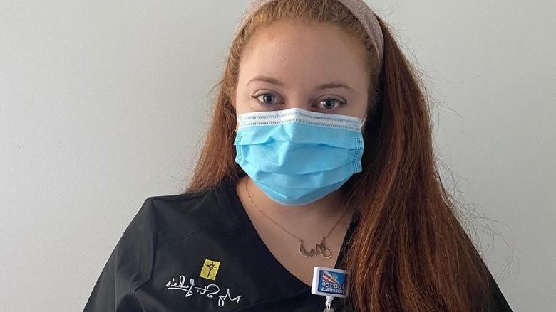 young woman in scrubs and face mask